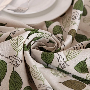 Detailed macro view of pastoral green leaf pattern on off-white cotton linen tablecloth