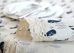 Detail of whale pattern linen tablecloth with decorative beige crochet lace edge