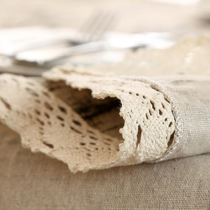 Detailed macro of rustic linen texture and intricate crochet lace edge on a beige tablecloth