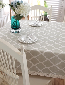 Detailed view of grey geometric table cloth with white lace edge and tassel accents
