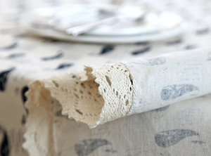 Detailed view of ocean whale print fabric with wide crochet lace edge on linen tablecloth