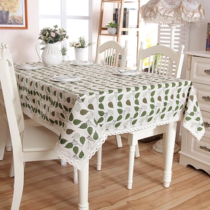 Detail of green leaf prints and wide lace trim on a cream rectangle tablecloth