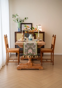 Close-up of tropical jacquard table runner with pink flowers and green fringe tassels