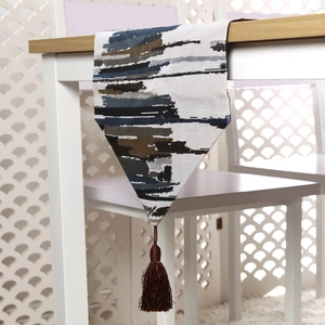 Detailed view of abstract painted table runner featuring deep blue stripes and brown tassels