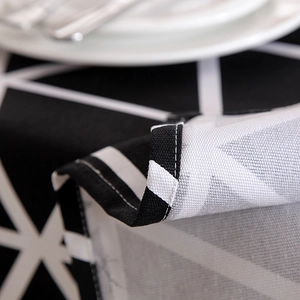 Macro shot of hemmed edges and stitching detail on black and white geometric canvas tablecloth