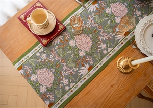 Detailed jacquard weave of floral table runner with tassels on a wooden dining table