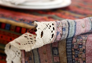 Detail of bohemian striped tablecloth with intricate lace trim and woven texture