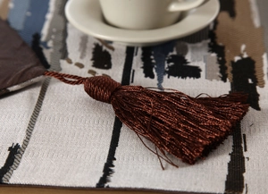 Detail of colorful woven table runner fabric with elegant dark brown decorative tassels