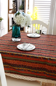Detail of colorful bohemian striped tablecloth featuring intricate lace edges and tassels