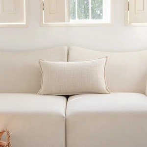 Detail of cream rectangular cushion cover with fine checkered texture and ruffled edges