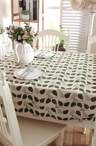 Detail of green leaf prints and white hollow lace edges on a cream cotton linen tablecloth