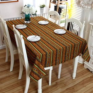 Close-up of bohemian striped linen tablecloth with rustic fringe and golden accents