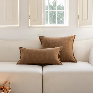 Close-up of brown jacquard checkered pillow covers on a white sofa in minimalist style