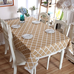 Detailed close-up of khaki table cloth with white quatrefoil pattern and lace edge trim