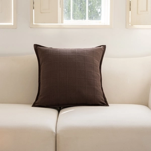 Detail of dark brown checked jacquard pillowcase with elegant ruffled edge on sofa