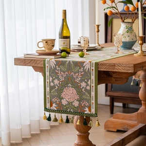 Tropical rainforest floral jacquard table runner with decorative fringe on a wooden table