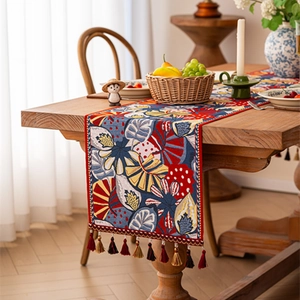 Bohemian tropical floral table runner with colorful tassels on a wooden dining table