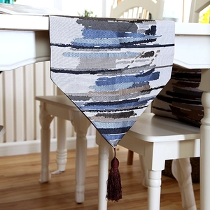 Detail of blue and grey woven table runner featuring silk tassels and abstract stripes