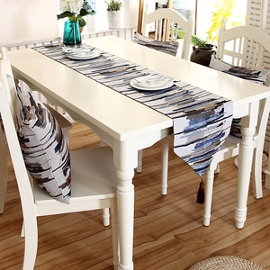 Detailed view of striped table runner with tassels and matching cushions on table