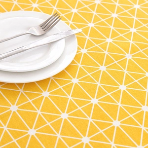 Detail of yellow geometric checkered tablecloth with modern white lines and tableware