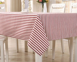 Detail of red and white striped cotton-linen tablecloth with clean hem on a dining table