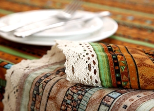 Detail of ethnic striped table runner with intricate white crochet lace border