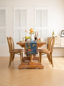 Detail of blue moon and castle tapestry table runner with colorful tassels on wood table