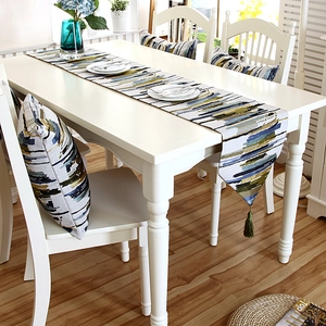 Close-up of modern abstract woven table runner and cushion with green fringe tassels