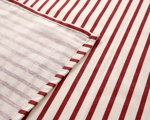 Macro detail of high-quality hemmed edges and stitching on red striped cotton tablecloth