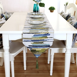 Close-up of colorful paintbrush striped table runner with a deep green tassel detail