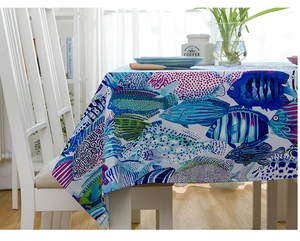 Detail of cotton tablecloth featuring colorful tropical fish print on a white table