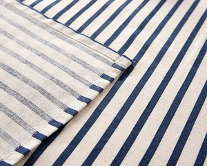 Detail of blue and white striped fabric showing tight weave and neat hem stitching