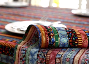 Detail of ethnic striped linen tablecloth with gold foil patterns and lace trim texture
