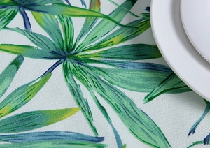 Detail of cotton canvas tablecloth featuring vibrant tropical leaf prints and woven texture