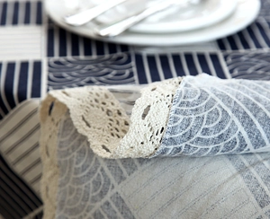 Detailed close-up of navy blue wavy pattern tablecloth with crochet lace edge detail