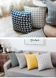 Detail of Nordic plaid and geometric cotton linen cushion covers on a grey fabric sofa