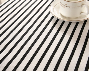 Close-up of minimalist black and white striped linen tablecloth texture with coffee cup