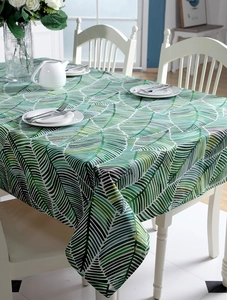 Detail of a thick cotton tablecloth with a green tropical leaf pattern on a white table