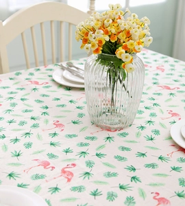 Detail shot of tropical flamingo and palm leaf prints on a beige linen tablecloth