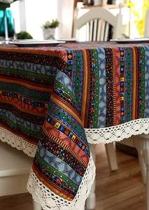 Close-up of bohemian linen tablecloth with colorful gold stripes and white lace trim