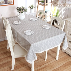 Detail of grey plaid tablecloth featuring delicate white lace edges and rustic cotton texture