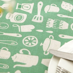 Detailed macro texture of a green linen tablecloth with cartoon kitchenware patterns