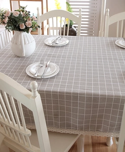 Detail of grey plaid tablecloth with white line pattern and delicate lace border