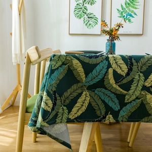 Thick cotton canvas tablecloth featuring tropical banana leaf patterns on a wooden table