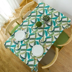 Thick cotton rectangular tablecloth with green tropical leaf prints in a cozy home setting