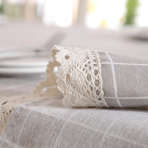 Close-up of grey and white checkered tablecloth with decorative cream lace edges
