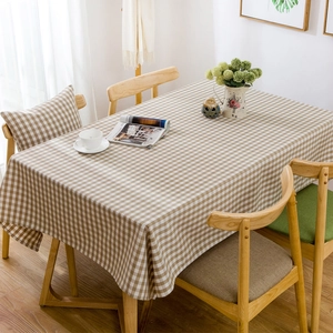 Detail view of beige gingham tablecloth with natural drape on a wooden dining table
