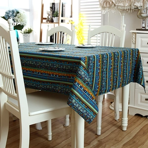Detail of bohemian gold-striped linen tablecloth with lace edges on a white dining table