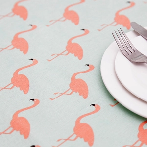 Close-up of pink flamingo pattern on mint green linen tablecloth with dinnerware