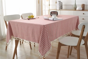 Detail of red and white striped cotton tablecloth featuring elegant white tassel fringes